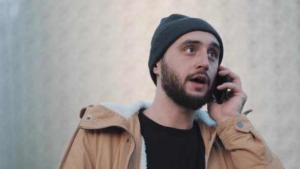 Happy Young Beard Man Calling on Mobile Phone Walking in the Street Near Shopping Mall 