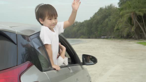 Happy asian family driving a car go to travel trip with excited on the beach for recreation together