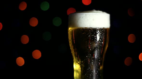 A Glass of Cold Beer on a Black Background with Colored Lights