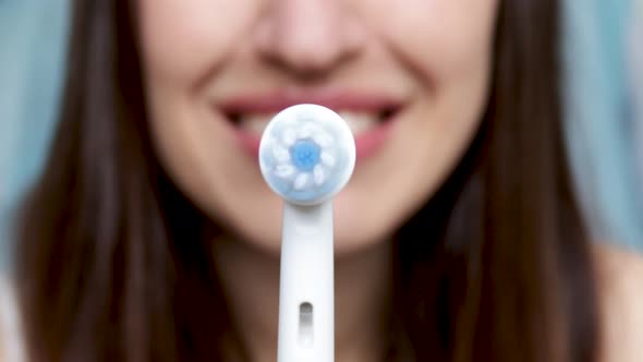 smiling young woman holding electric toothbrush, turning on, rotative moves. dental care concept. or