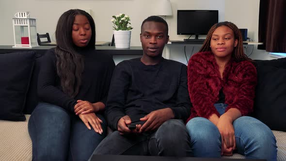 Three African Friends Watch Television in Living Room They Are Talking About Something