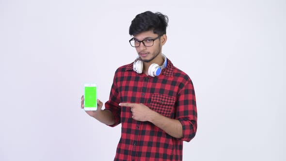 Young Happy Bearded Indian Hipster Man Showing Phone and Giving Thumbs Up