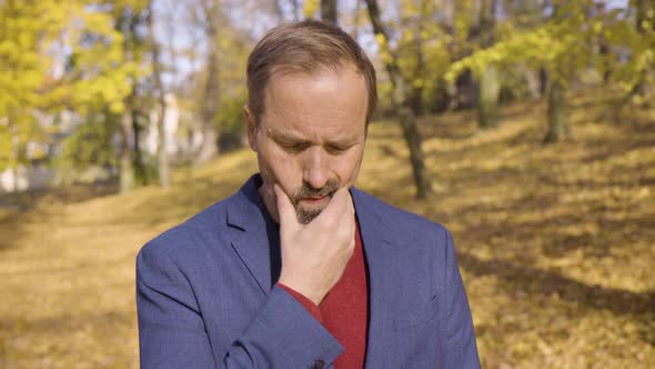 A Middleaged Handsome Caucasian Man Thinks About Something in a Park in Fall  Closeup