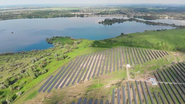 Aerial View on Solar Power Station in Green Field Near River at Sunny Day