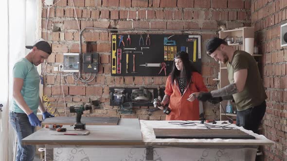 Two Men and Woman Working in Comfortable Clothes and Caps Making Furniture