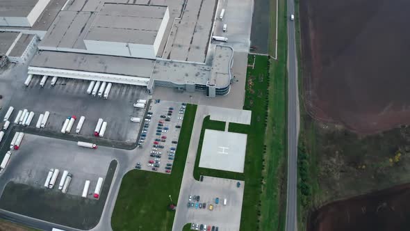 Industry near the road. Parking zone with cars and trucks on the industrial territory on field.