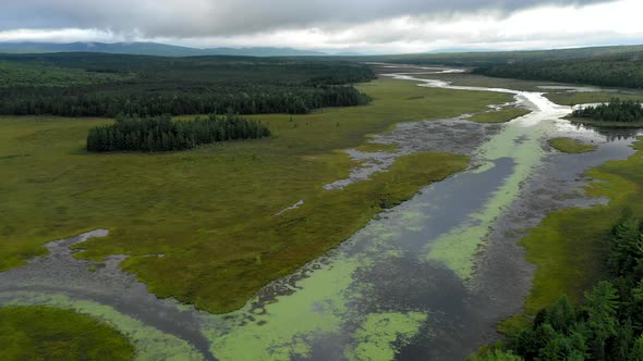 Aerial shot dropping down above the still waters of Shirley Bog winding through the Maine countrysid