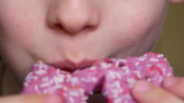 Close-up of a caucasian boy 7 years old eats an appetizing sweet dessert donut in glaze.