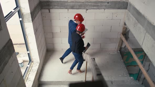 Caucasian male and female architects walking and supervising on construction site.