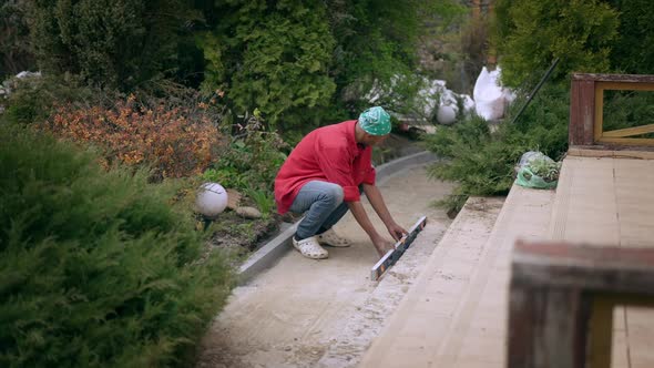 Wide Shot of African American Young Handsome Man Using Level Ruler Repairing Stairs on Backyard