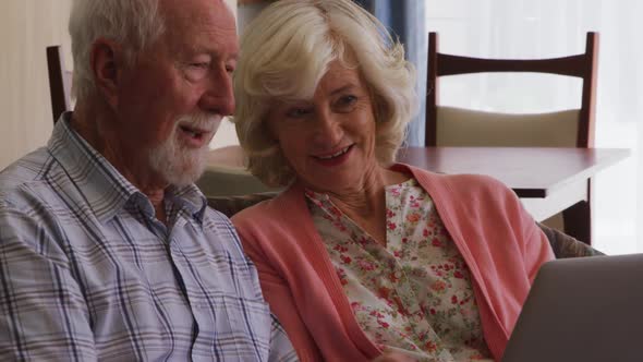 Senior couple in social distancing using laptop