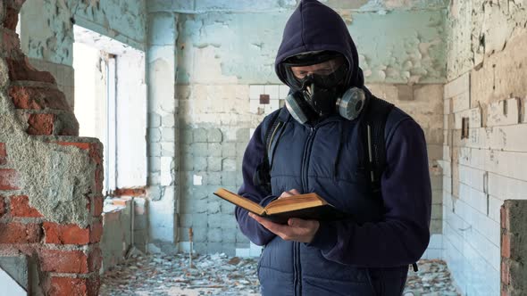 Man in Gas Mask Reading Book in Destroyed Building