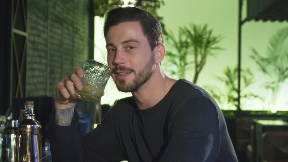 Handsome Cheerful Young Bearded Man Drinking at the Local Bar