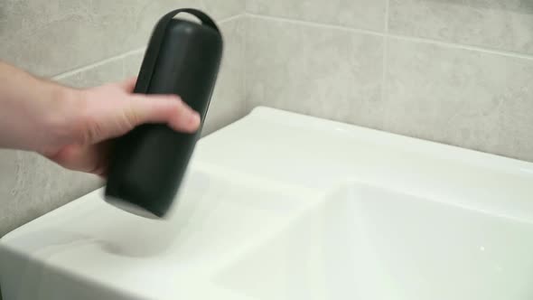 A Man Plays Music on a Bluetooth Speaker in a Bathroom