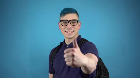 A Student in Glasses with Blue Hair Shows a Thumb. Alternative Man with a Briefcase Behind His Back