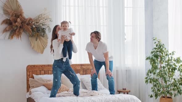 Caucasian Young Family Parents Having Fun at Home in Bedroom Standing on Bed Strong Adult Mother Mom