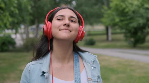 Beautiful Girl in Red Headphones Walking Down the Street and Listening To Music. Portrait