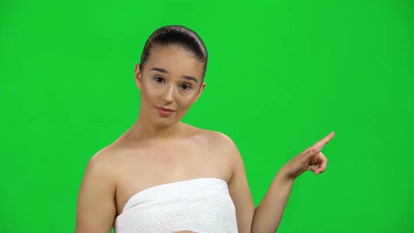 Young Woman Pointing Finger To Side on Green Screen at Studio