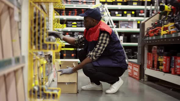 Male Worker Refill Goods on Lower Shelves of Hardware Store