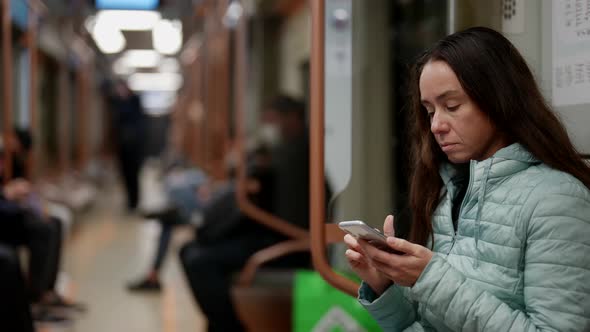 Woman Without Face Mask is Sitting in Train of Subway and Using Smartphone