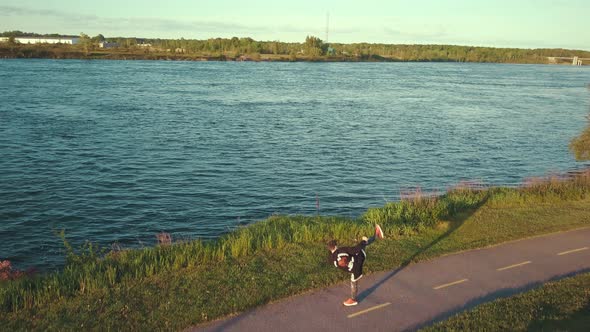 A young MMA fighter trains and shadow boxes outside next to a large river in the morning sunshine as