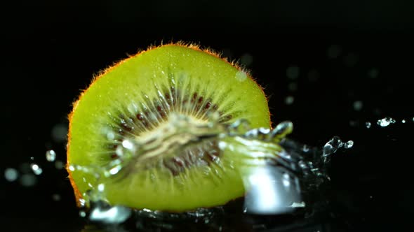 Super Slow Motion Shot of Falling And Splashing Kiwi Slice Isolated on Black Background at 1000Fps.