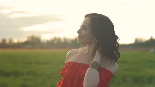 Portrait of a Beautiful Spanish Brunette Woman in a Red Dress at Sunset in a Wheat Field