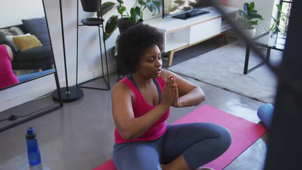 African american female plus size sitting on exercise mat meditating