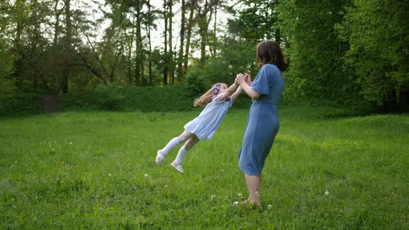 Mother with Daughter in Blue Dresses Are Spinning