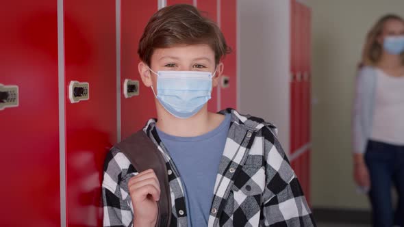 Video portrait of smiling teenager in protective face mask at school.