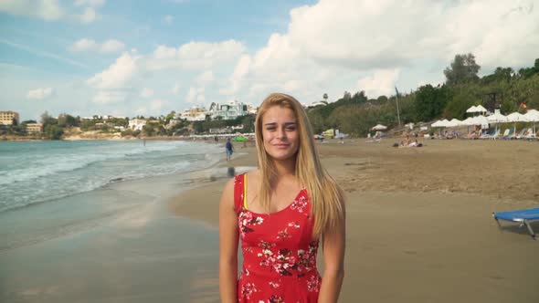 Portrait of Young Woman with Blond Hair Standing at the Beach