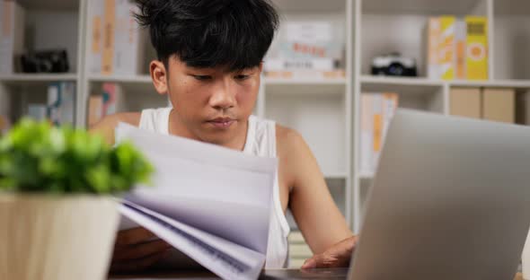 Tired man using laptop and looking document