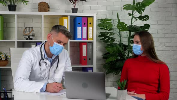 Doctor man and patient woman in protective masks communicates talk listen