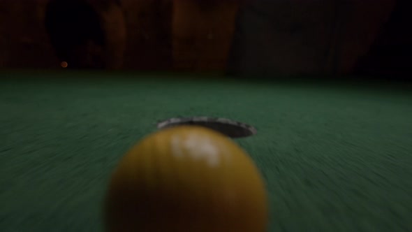 A yellow mini golf ball falls into the golf hole and bounces in the pocket on a course.