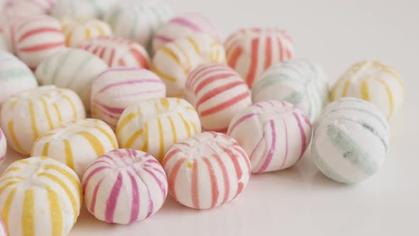 Striped round candies on white background 4K tilting footage