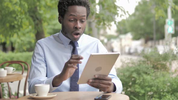 Wow, Shocked African Businessman Using Tablet while Sitting in Outdoor Cafe