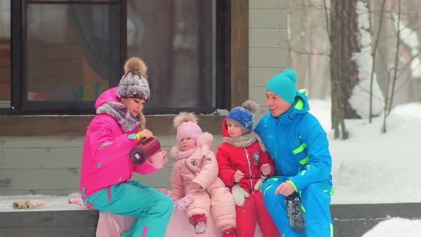 Parents and Children Drink Tea Sitting on Building Porch