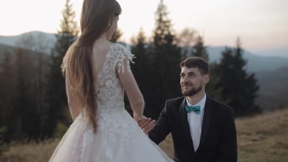 Newlyweds. Caucasian Groom with Bride on Mountain Slope. Groom Proposes