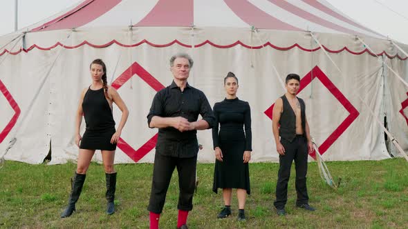 Group of circus performers standing in front of tent