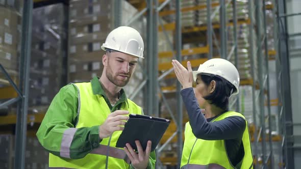 Two Employees Discussing Work with Tablet Computer at Logistics Warehouse. Colleague, Clipboard