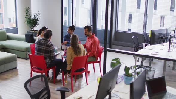 Diverse group of business colleagues sitting on chairs discussing