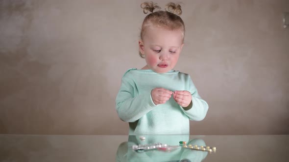 A little girl finds pills on the table and plays with them