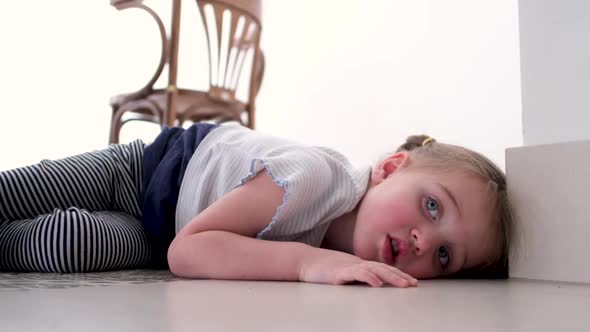 Child Lies on the Floor and is Bored