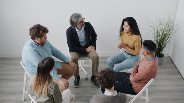 Distressed Asian Woman Speaking at Group Therapy Session Sharing Difficult Situations