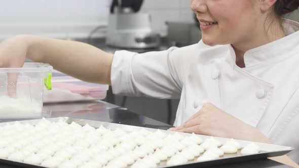 Cropped Shot of a Female Confectioner Decorating Meringues with Coconut Flakes