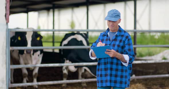 Farmer Gesturing While Writing on Clipboard Against Barn