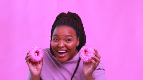 Multicultural Female Holding Delicious Sweet Donut in Pink Studio Background