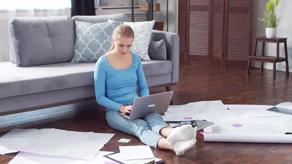 Young woman works with documents using a laptop at home.
