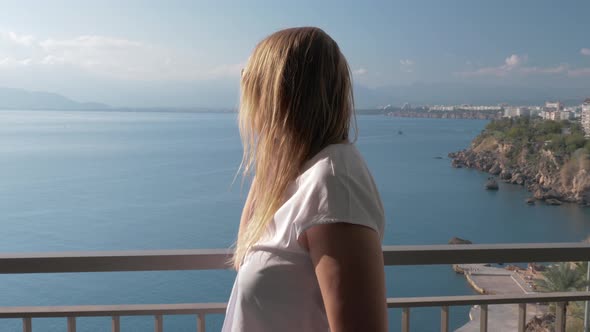 A Fair-haired Woman Talking To a Phone on a Hotel Balcony Near the Sea Landscape