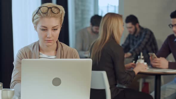 Portrait of Smiling Pretty Young Business Woman Putting Off Glasses Sitting in Cafe Woth Laptop